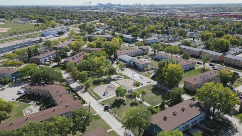 A drone shot shows rows of townhouses with trees and streets receding off into the distance.