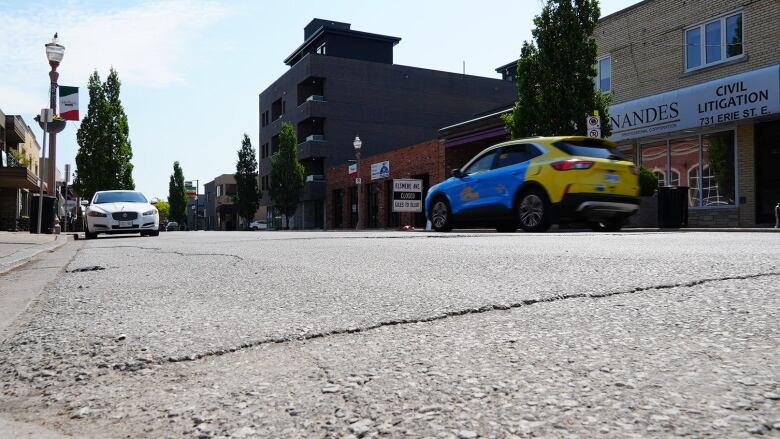 Close up of a roadway with buildings and a taxi in the background.