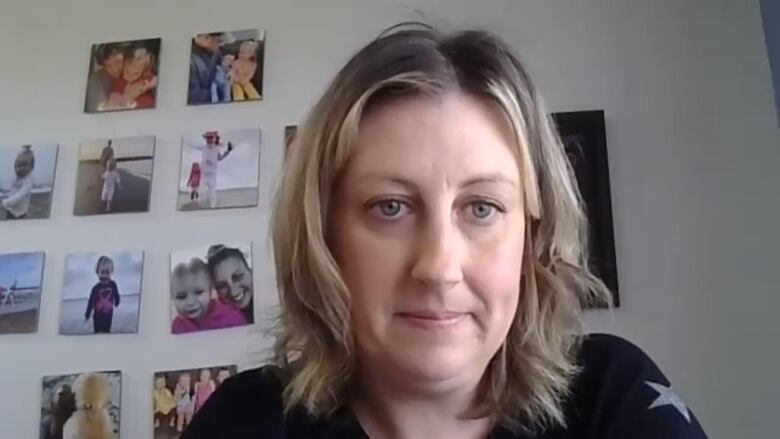 Woman in black sitting with photos of children in background