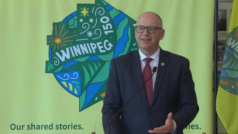 A smiling man in a suit stands at a podium