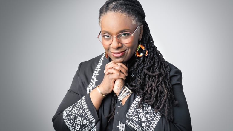 A portrait of a woman clasping her hands together. 