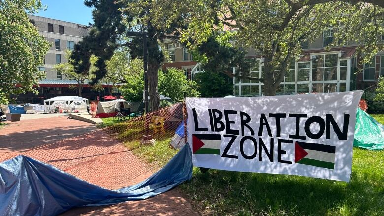 Tents are seen behind a banner that reads 