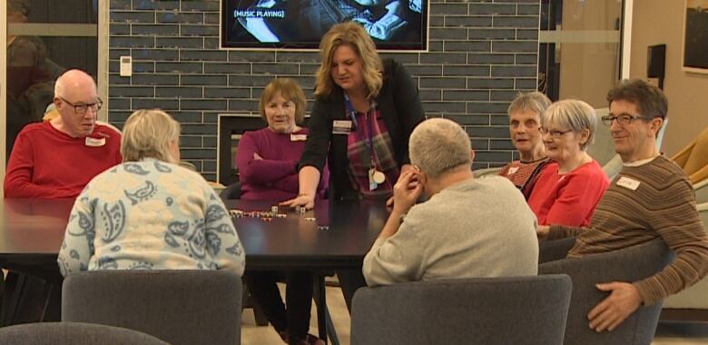 A group of seniors sit around a table playing a game with poker chips