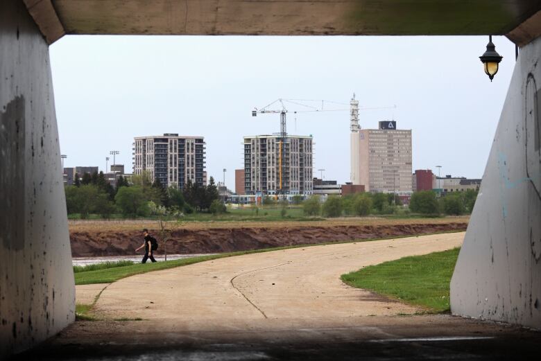 Several tall buildings with a crane viewed through a tunnel opening. 