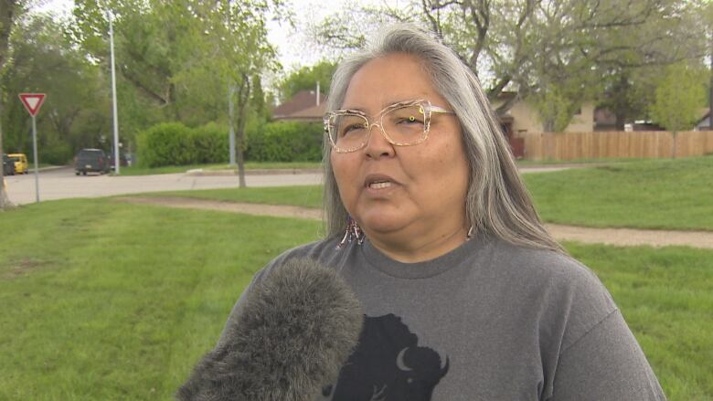 A woman in a grey shirt with a buffalo on it speaks to media. 