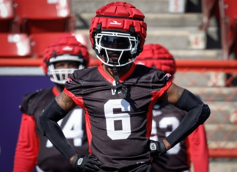 A football player wearing black training uniform and a red helmet is pictured.