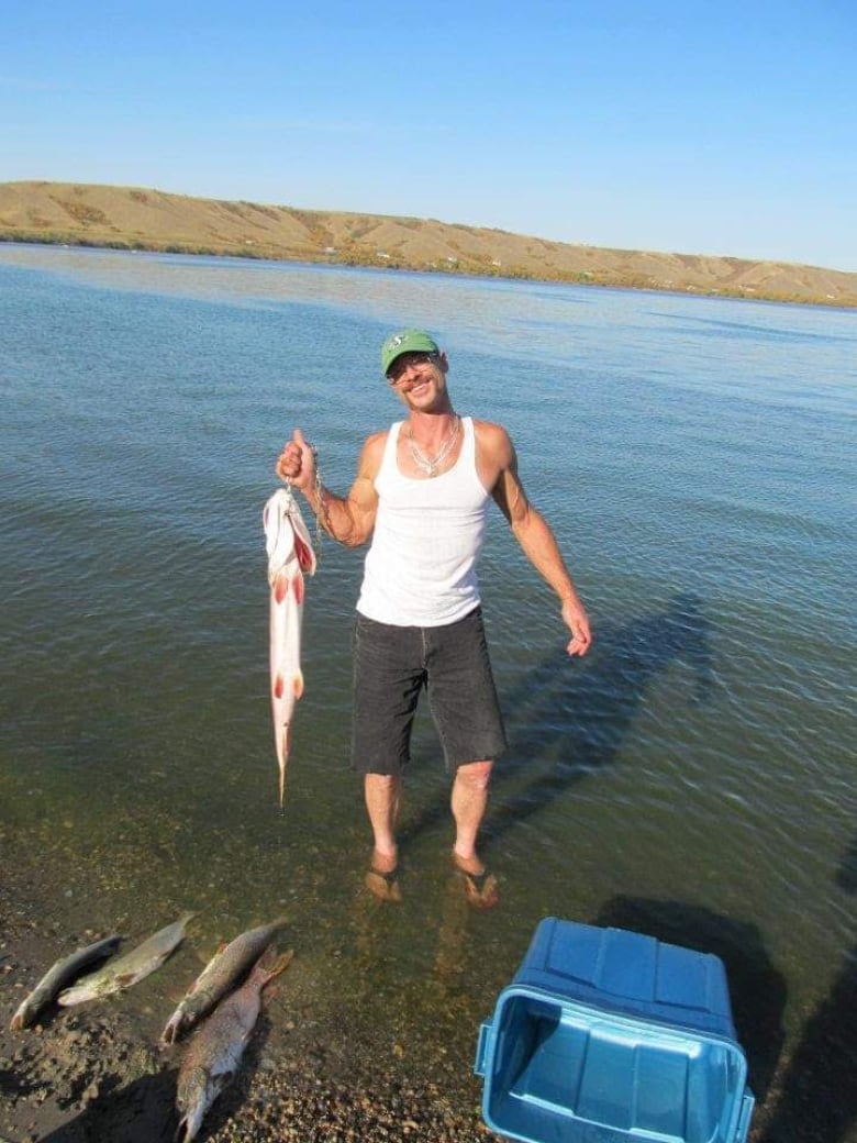 A man stands in a lake with a fish.