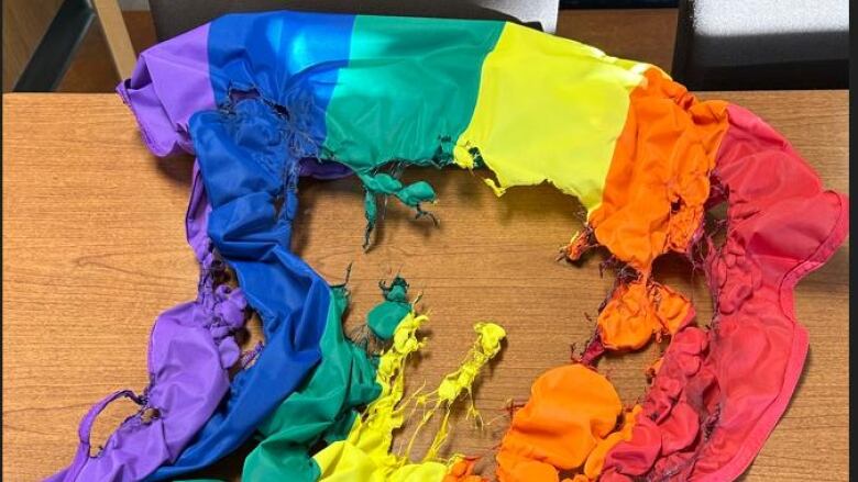 A Pride flag burned lies on desk