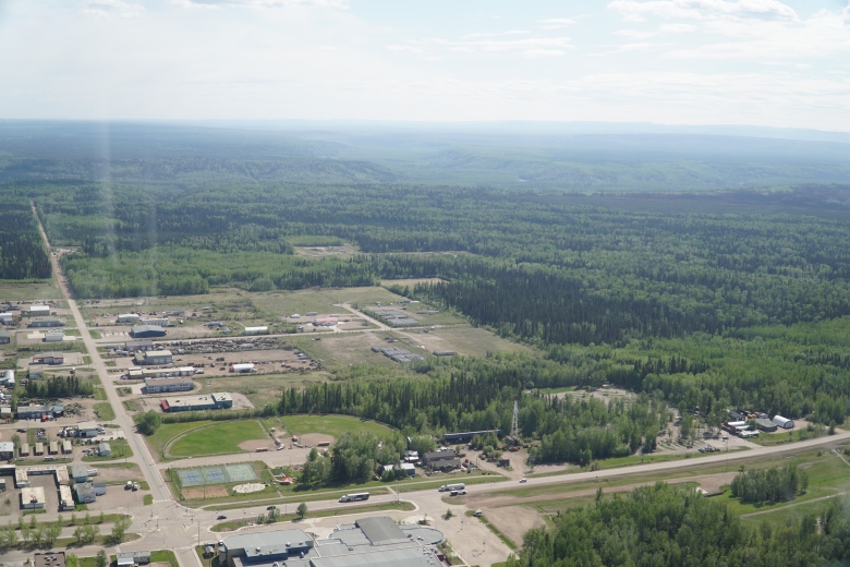 An aerial view of a region affected by the Parker Lake Wildfire, an industrial area shows trucks and parking lots and warehouse buildings