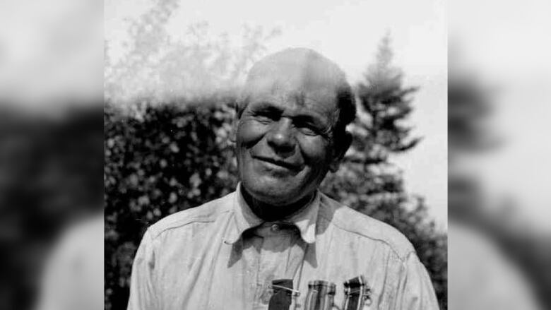 An Indigenous man is seen wearing war medals on his shirt.