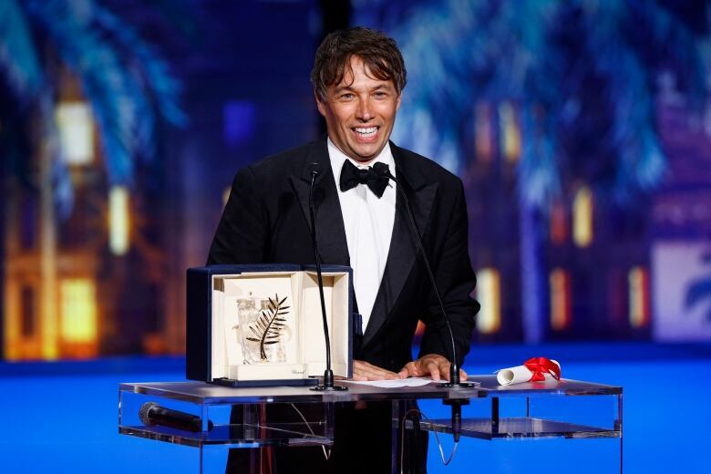 A person smiles while standing at a lectern that's displaying an award.