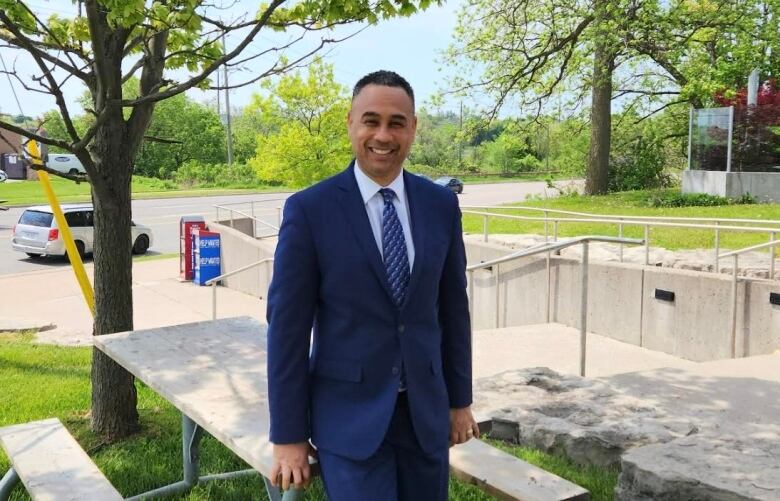 man in suit stands at picnic table outside