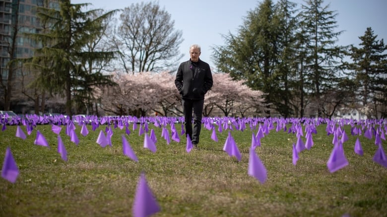 A man stands among a wave of purple flags.