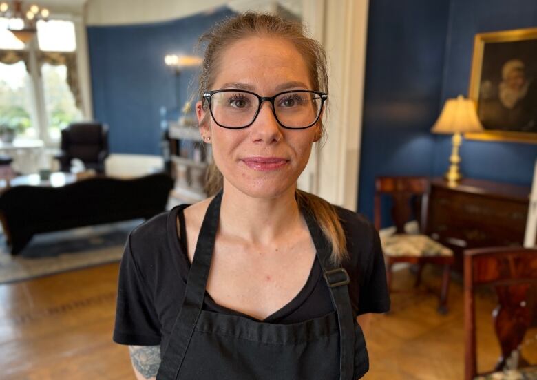 A chest-up shot of a woman wearing glasses and a black t-shirt.