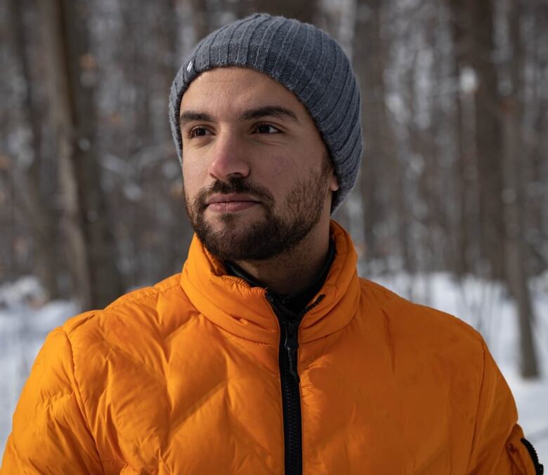 Person wearing a bright jacket, not looking at the camera but off to the side, in a wintry landscape.