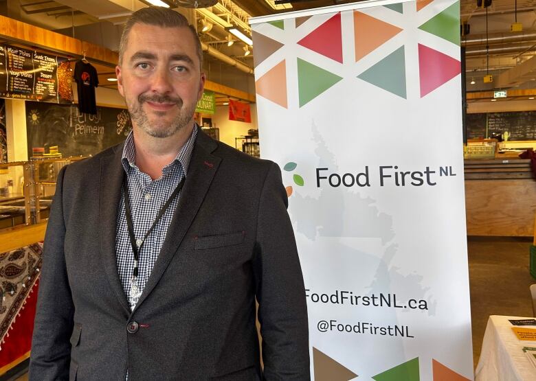 A man stands in front of a sign that reads 