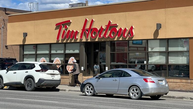 Cars are seen parked on the street in front of a Tim Hortons restaurant.