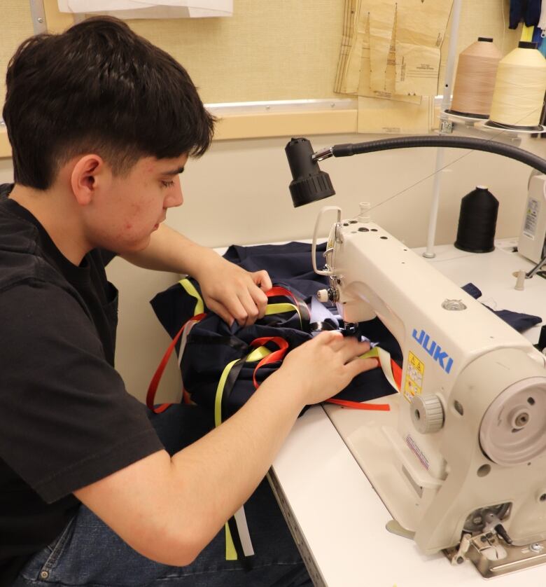 A young man works at a sewing machine.