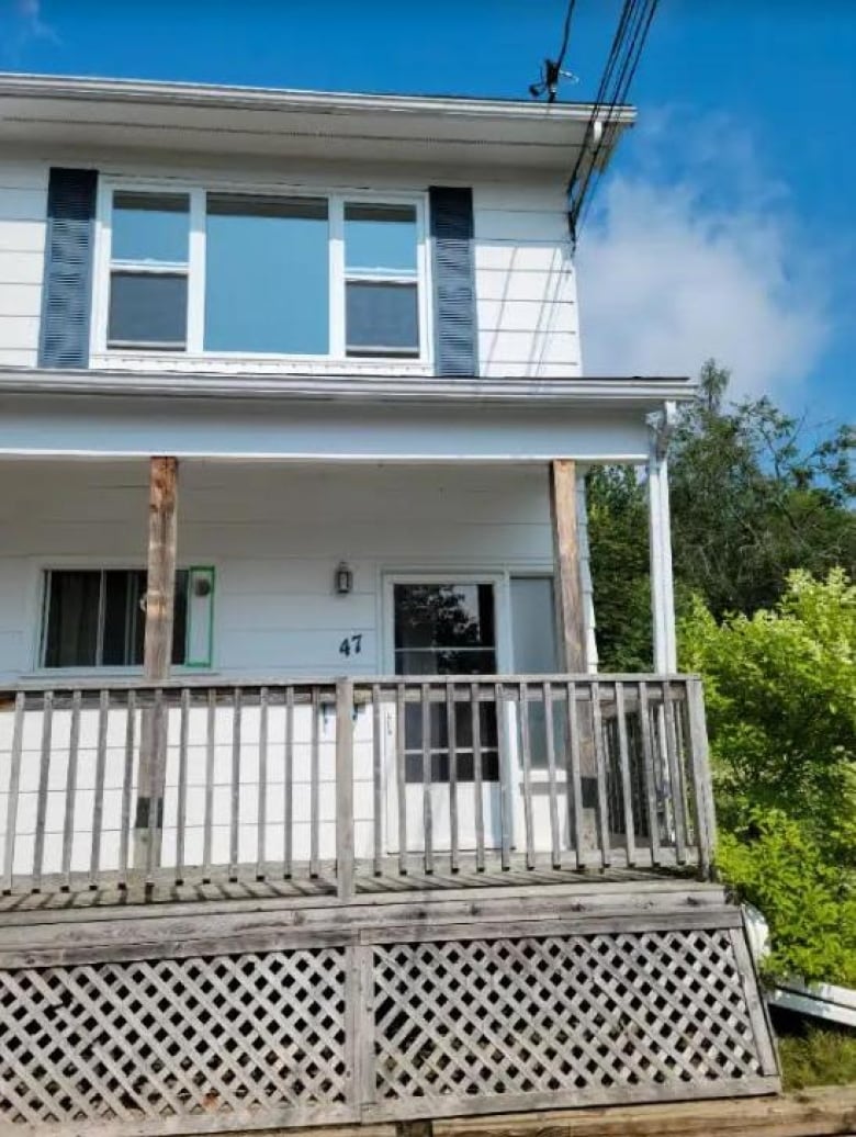 A white house with a front porch and the number 47 on the siding