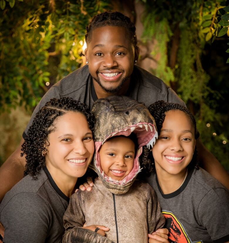 A young Black family standing on a sidewalk together.