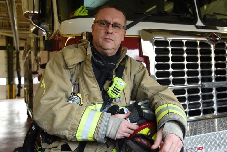 Firefighter Rob Leathen wearing his gear and standing in front of a fire truck.