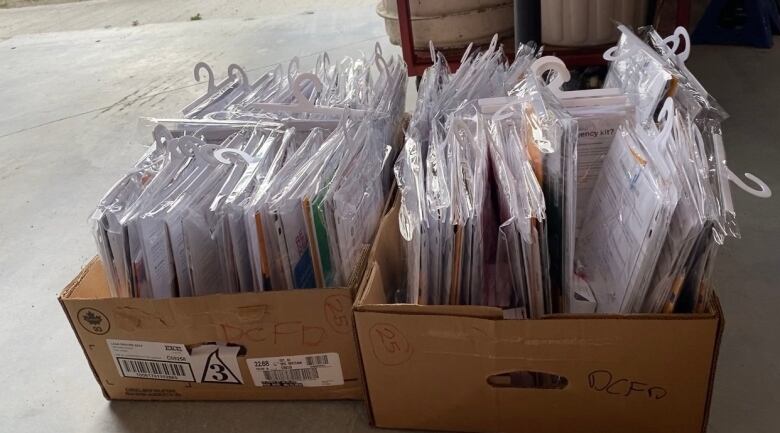 Boxes containing papers wrapped in plastic covers sit on the floor.