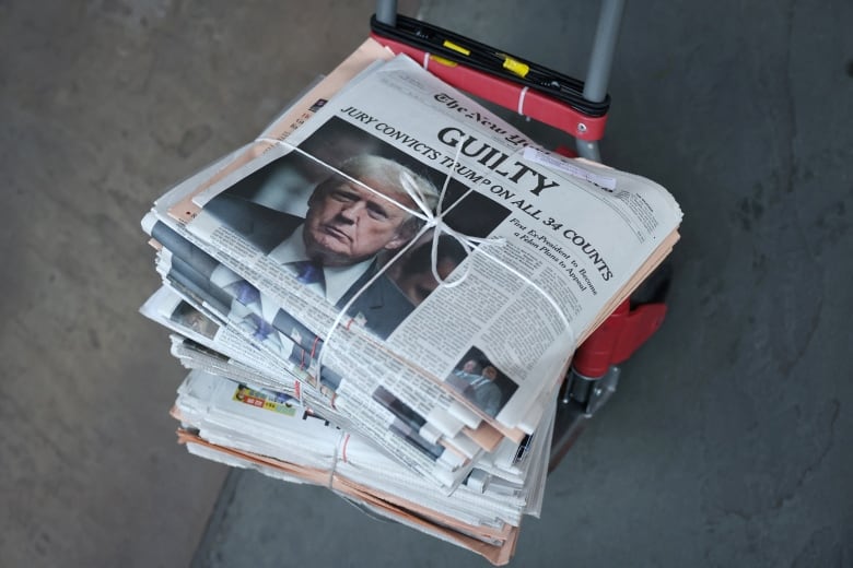 A stack of newspapers, with a copy of the New York Times on top, with a front page explaining the outcome of the verdict in former U.S. president Donald Trump's hush-money trial.