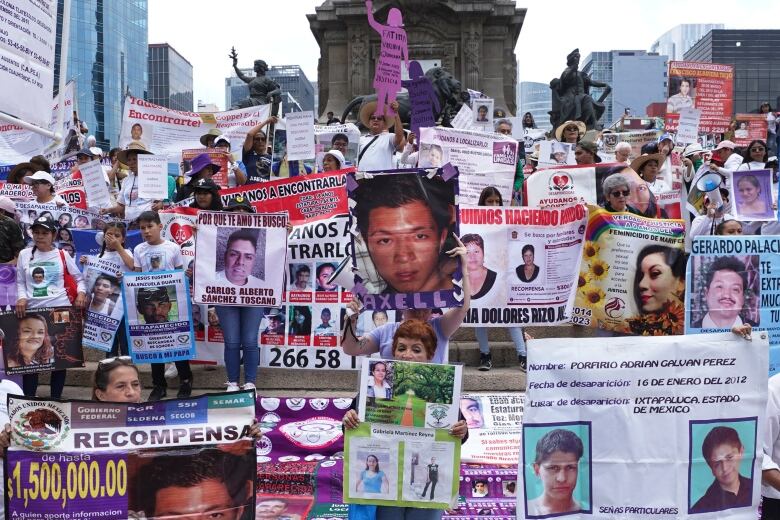 A group of mothers holding pictures of their children march in a demonstration.