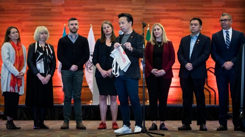 Eight people are pictured standing on stage