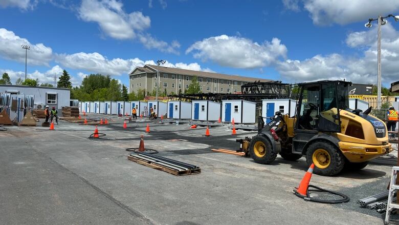 A row of shed-like buildings near a yellow excavator.