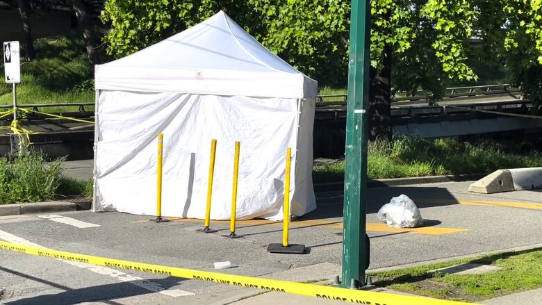 A white tent is shown with yellow police tape in front of it.