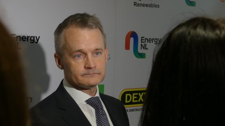 A man in a suit looking at reporters.