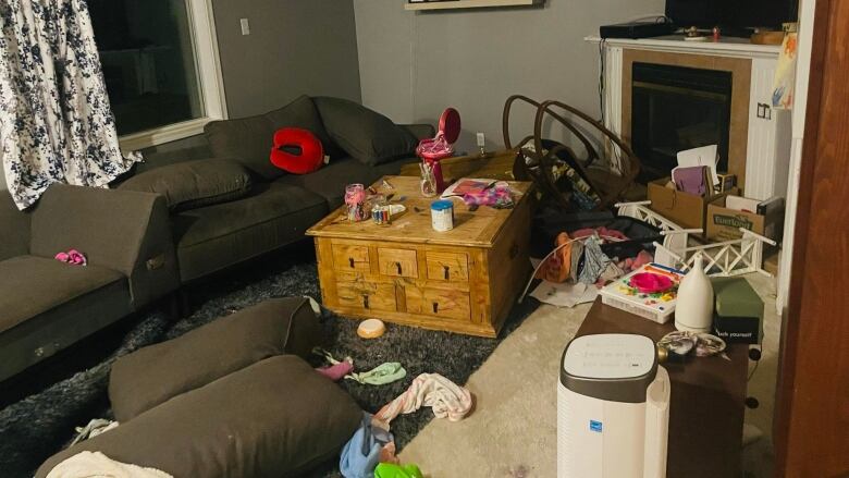 A living room is shown with furniture knocked around, couch cushions on the floor, and stuff everywhere.