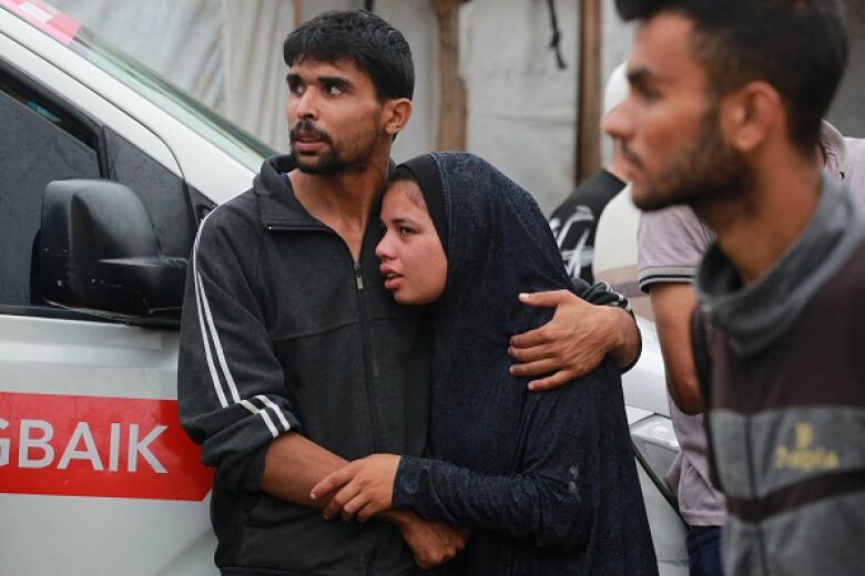 A man comforts a young woman, who is crying.