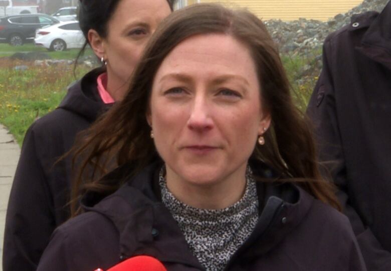 Woman with brown hair with people standing behind her