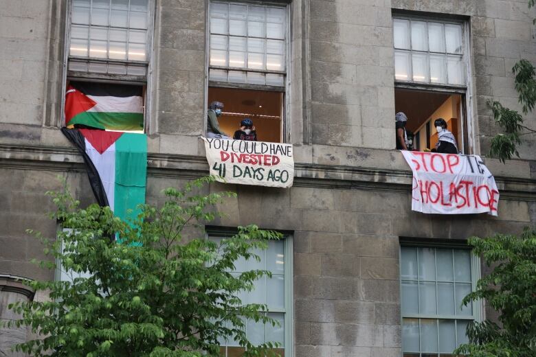 palestinian flag and signs saying 'you could have divested 41 days ago' and 'stop this scholasticide' hanging from open windows