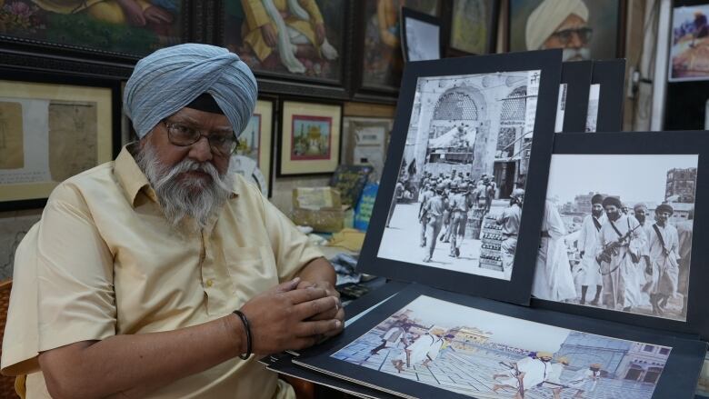 A person sits a table that is displaying three large photos.