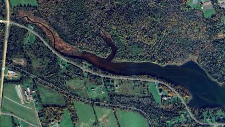 A satellite view of a river meandering through forested land. 