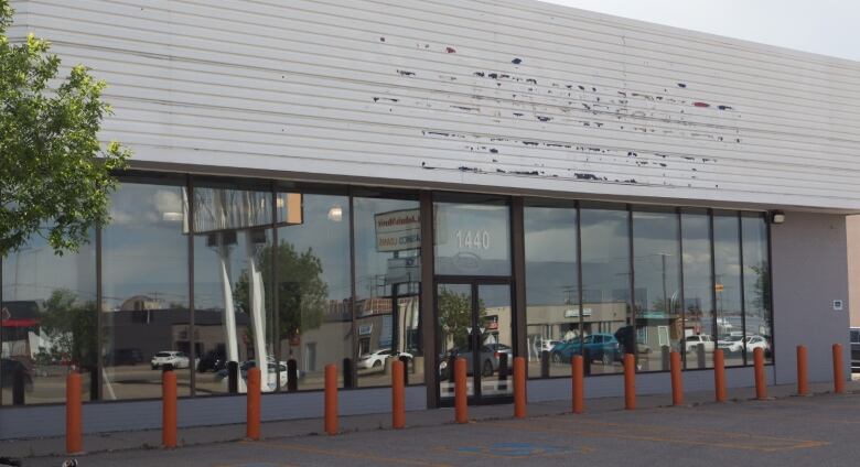 A vacant building with orange bollards in front of it.