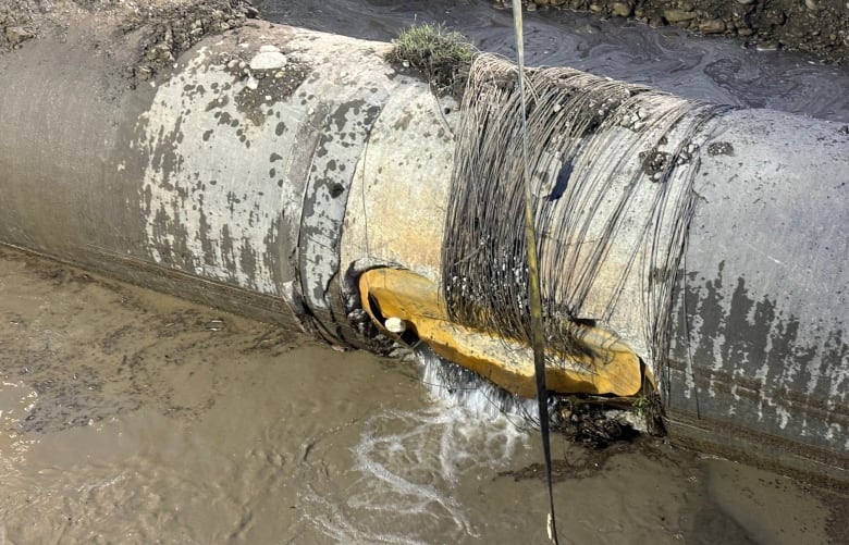 A massive water main pipe is shown, damaged and exposed.