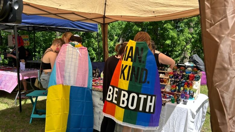 Two people with pride flags over their shoulders. 