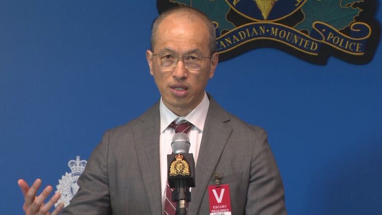 An Asian man with glasses stands at a podium.