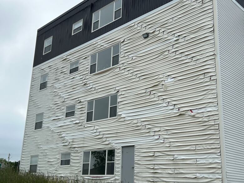 White building with siding damaged.