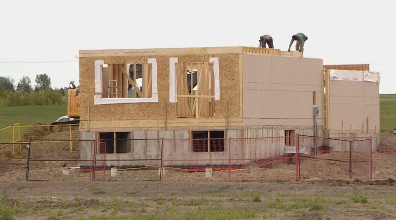 Two men stand atop a construction project.