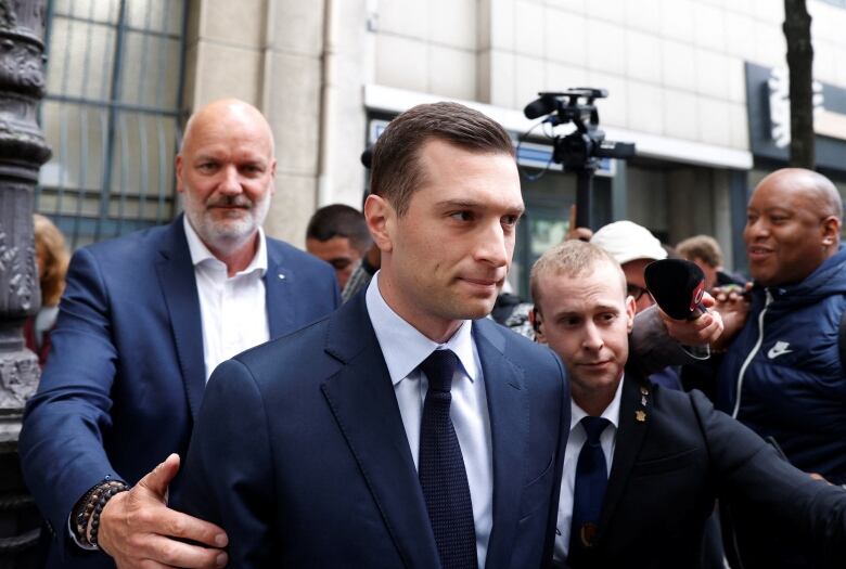 A man walks through a crowd of journalists.