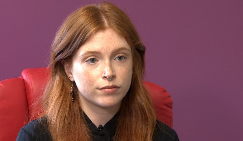 Woman with red hair sitting in red chair.