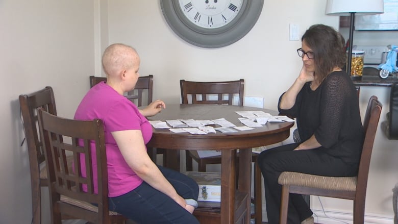 Emma and Tracie sit at the kitchen table with the gift cards and corresponding receipts laid out on the table. 