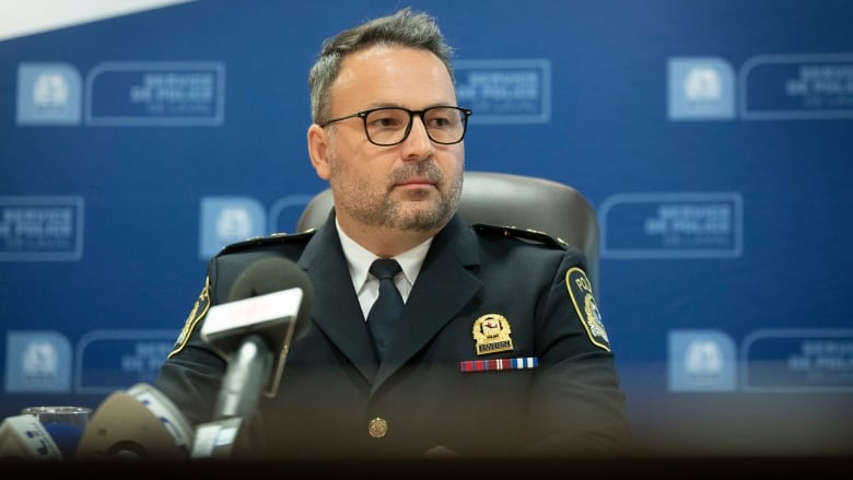 A police officer sits in front of a microphone.