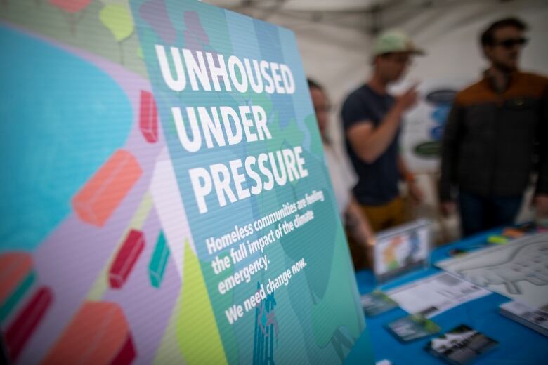 People stand at a booth behind a sign that reads 