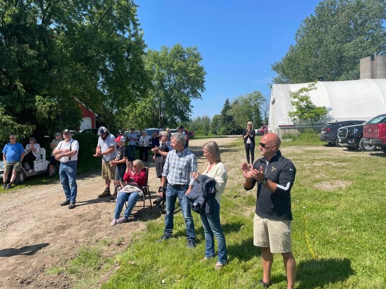 People clapping in front of a barn